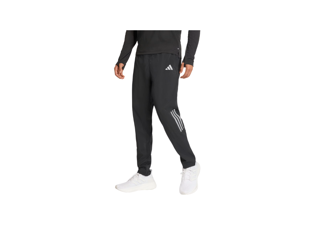 Person wearing black Adidas tracksuit with white stripes on a white background